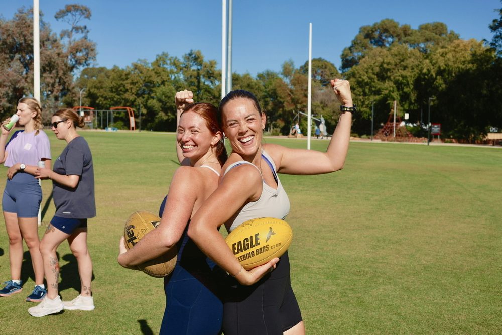 Two newbies flexing with footies at an AFL social