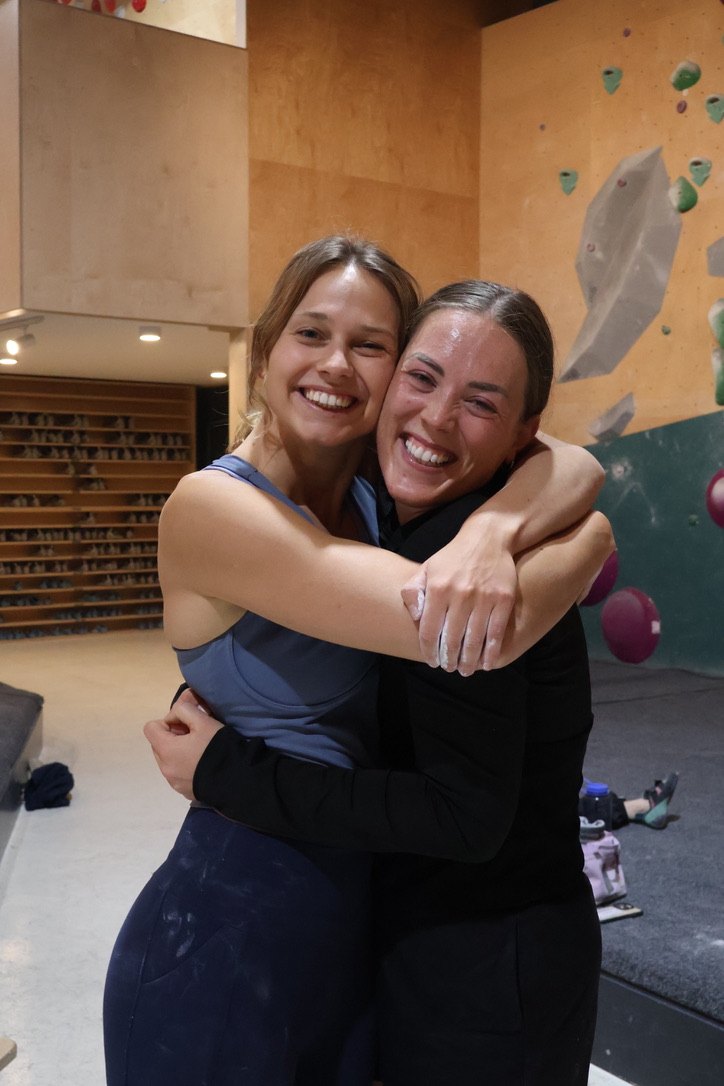 Two newbies hugging and laughing at a bouldering social