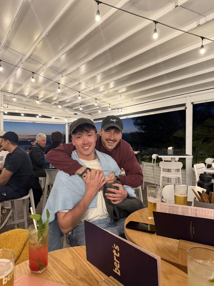 Two mates hugging over drinks after a social