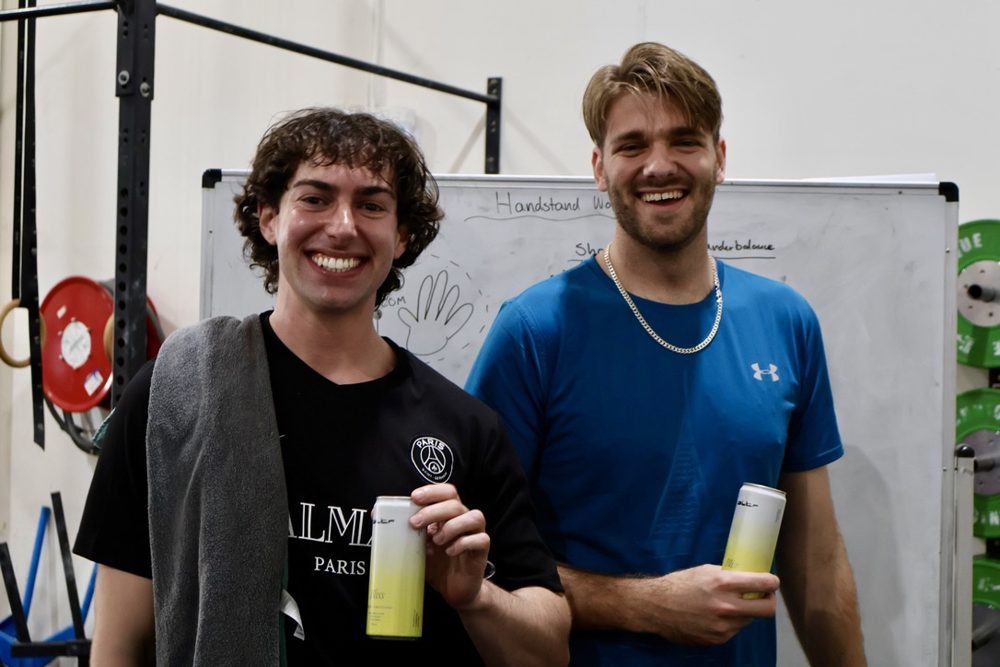 Two newbies smiling with drinks after a handstand workshop