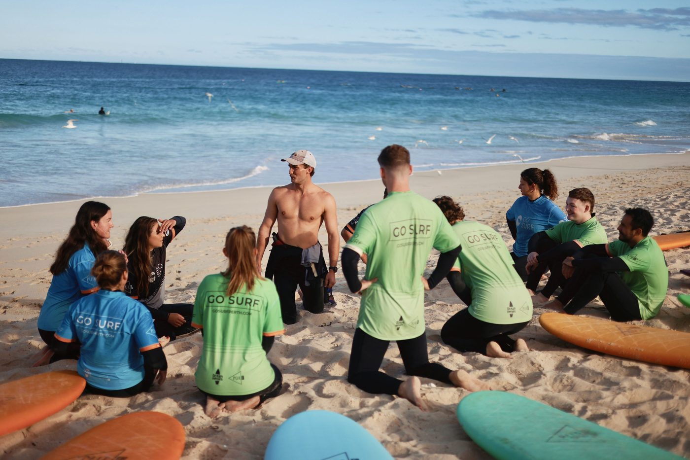 Newbies sitting together in a circle on the beach after a surf social