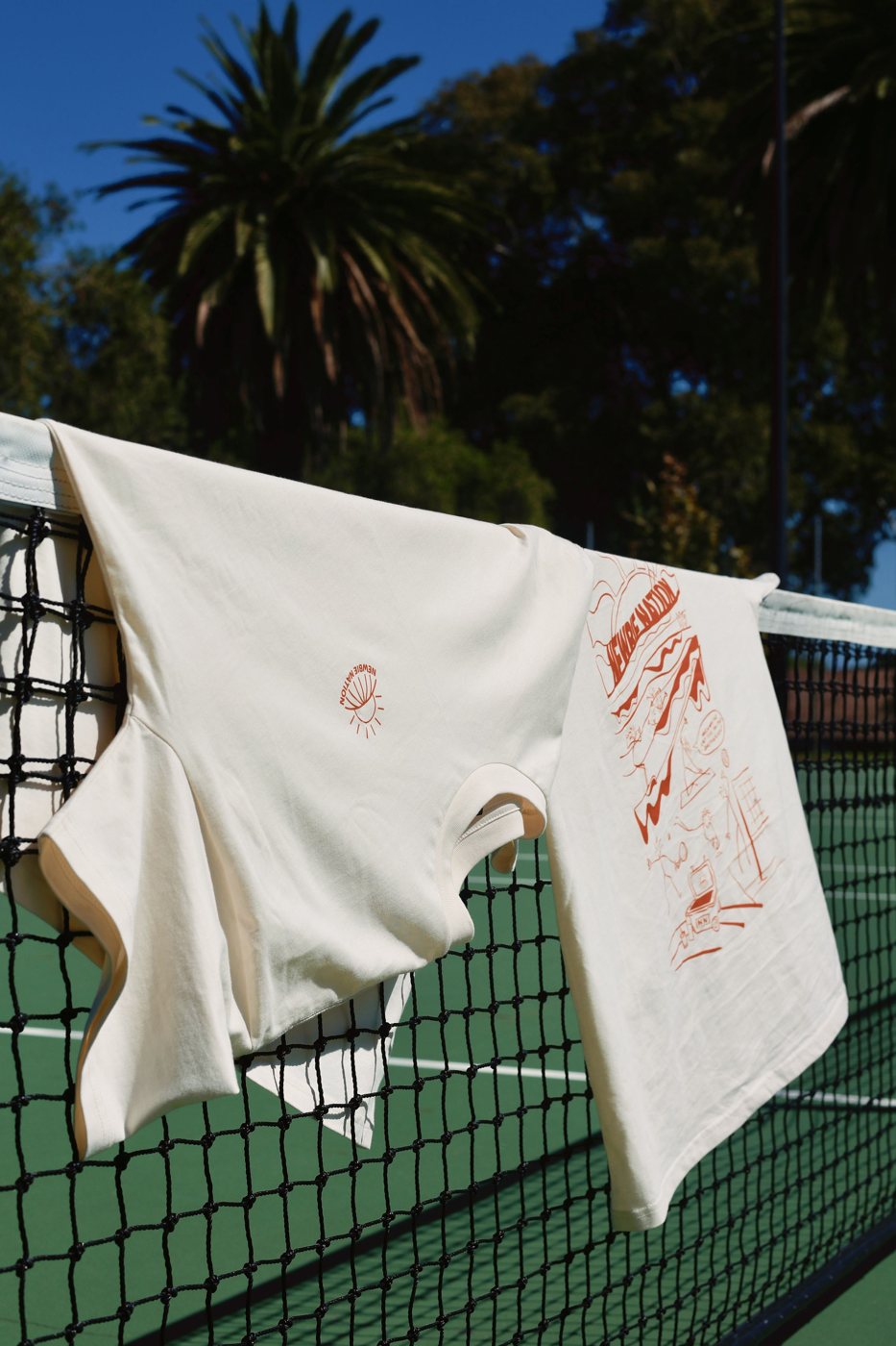 Try Something New Tee hanging on a tennis net, showing the front logo and back print